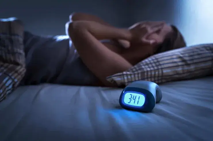 Pessoa na cama olhando o despertador durante a noite