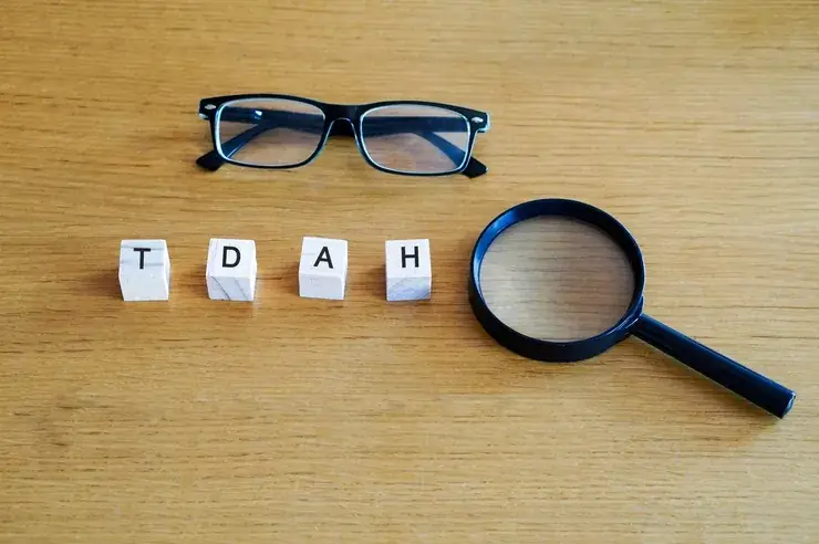 Cubos com as letras TDAH ao lado de óculos e lupa